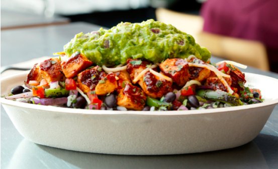 A Chipotle Burrito Bowl with black beans, fajita veggies, adobo chicken, fresh tomato salsa, monterey jack shredded cheese, and topped with guacamole.